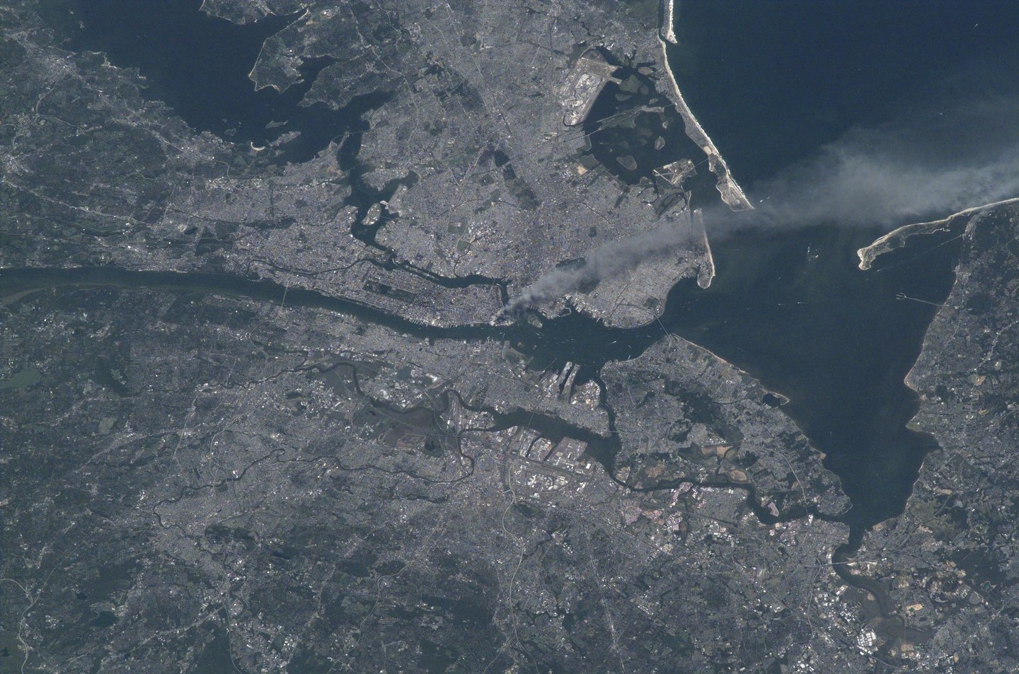 A view of New York City, and surrounding areas, as seen from space. Near the tip of Manhattan, at the center of the photo, a plume of smoke can be seen, extending into the sky and across the bay. Credit: NASA/Frank Culbertson